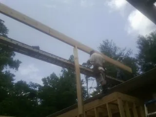 Carpenter setting a ridge beam over a new addition frame — Ice Dam Removal by Roofing Brothers in Lubbock
