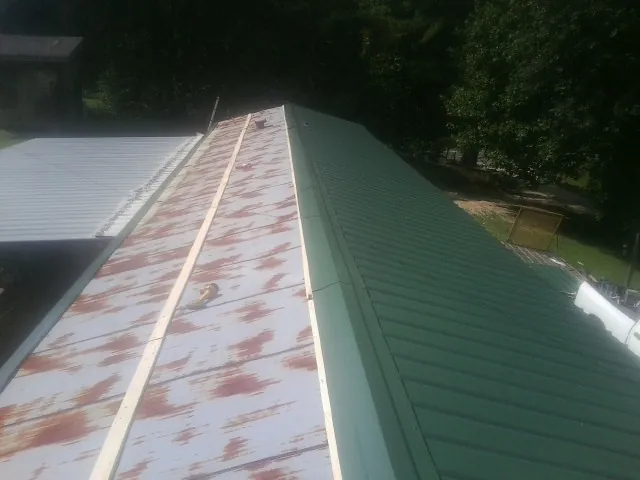Old rusted panels beside newly installed green metal roofing — Wind Damage Roof Repair by Roofing Brothers in Lubbock