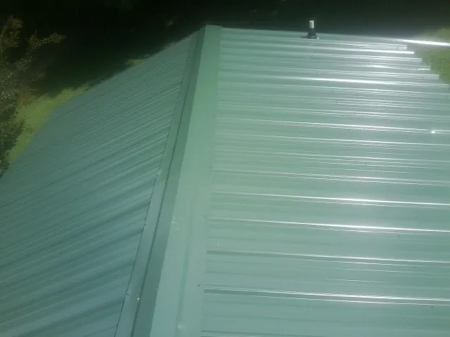 New green metal panels meeting at the ridge of a roof — Flat Roof Repair work by our crew in Lubbock