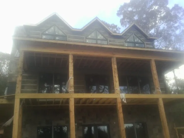 Dormers and porch framing on a large log home under construction — Roof Coating work by our crew in Lubbock