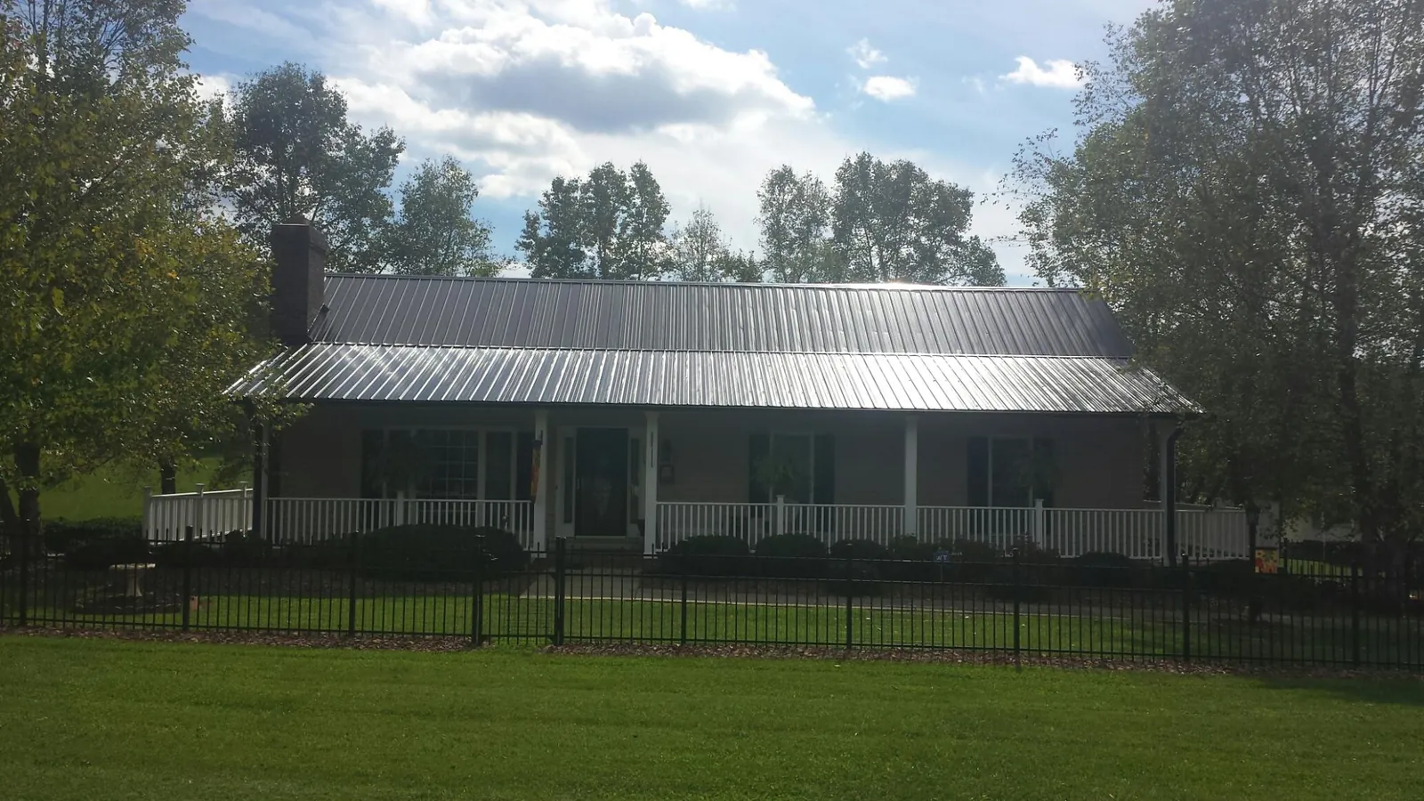 Gray metal roof on a brick ranch with a full width front porch — Gutter Guard Installation work by our crew in Lubbock